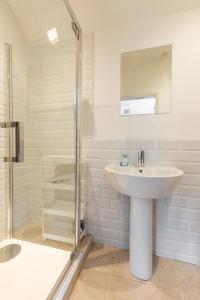 een witte badkamer met een wastafel en een douche bij St Clements House - Norfolk Holiday Properties in Norwich