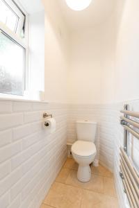 a white bathroom with a toilet and a window at St Clements House - Norfolk Holiday Properties in Norwich