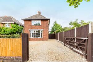 a brick house with a wooden fence and a gate at St Clements House - Norfolk Holiday Properties in Norwich