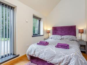 a bedroom with a purple bed with two purple towels on it at Burn View 