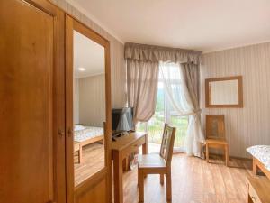 Schlafzimmer mit einem Schreibtisch, einem TV und einem Fenster in der Unterkunft Mini hotel Solnce Karpat in Poljana