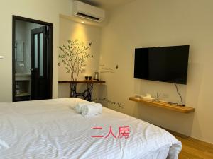 a bedroom with a bed with a flat screen tv on the wall at Chi Lan Liye Homestay in Chishang