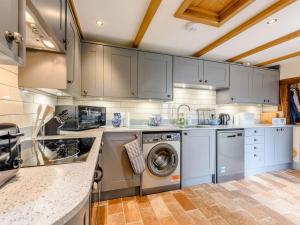a kitchen with gray cabinets and a washer and dryer at Sunny House By The Sea in Dymchurch