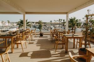 a restaurant with wooden tables and chairs and a marina at Lago Resort Menorca - Casas del Lago Adults Only in Cala'n Bosch