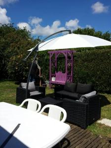 une table, des chaises, un parasol, une table et des chaises dans l'établissement Les Hortensias, à Plouha