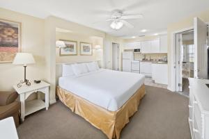 a bedroom with a large white bed and a kitchen at Holiday Inn Club Vacations Hill Country Resort at Canyon Lake in Canyon Lake