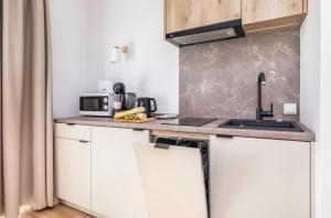 a kitchen with a counter with a sink and a microwave at Jantaris B1 - Apartament 20m od plaży in Mielno