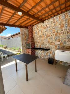 a patio with a table and a brick wall at Casa na Barra de São Miguel in Barra de São Miguel