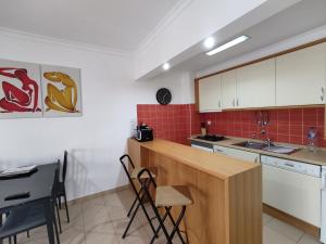 アルマカオ・デ・ペラにある1D Praia Mar - Casas & Papeisの白いキャビネット、テーブルと椅子付きのキッチンが備わります。