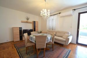 uma sala de jantar com uma mesa e cadeiras e um lustre em Apartments Petrovic em Malinska