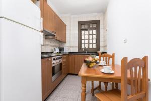 Una cocina con una mesa de madera y una mesa y sillas. en Home2Book Urban Gran Tarajal II, en Gran Tarajal