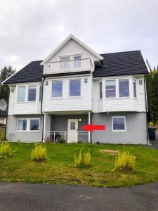 una casa blanca con una flecha roja delante de ella en Great apartment with a lovely view of the sea and mountains, en Kvaløya