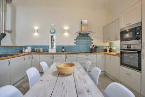 a kitchen with a wooden table and white cabinets at Finest Retreats - Min Yr Awel Barn in Fishguard