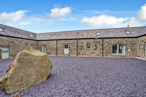 a large rock sits in front of a stone building at Finest Retreats - Min Yr Awel Barn in Fishguard