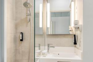 a bathroom with a sink and a shower with a mirror at B&B HOTEL Antwerpen Zuid in Antwerp