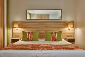 a bedroom with a bed with green pillows and a mirror at Hôtel Vacances Bleues Delcloy in Saint-Jean-Cap-Ferrat +37 photos