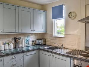 uma cozinha com armários brancos, um lavatório e uma janela em Seahorse Chalet em Humberston