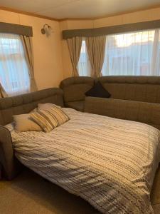 a bedroom with a bed with a couch and windows at Sunkist, Anderby Creek in Anderby