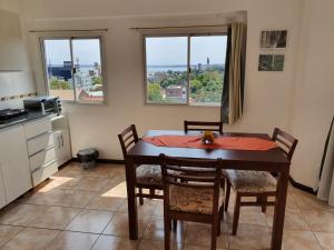 a dining room with a table and chairs and two windows at Departamento Augusta II in Posadas