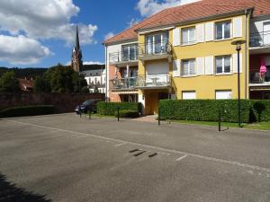 ein Parkplatz vor einem gelben Gebäude in der Unterkunft Le Hameau in Mutzig