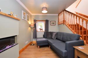 a living room with a couch and a staircase at Chapelton Cottage in Strachur