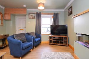 a living room with two chairs and a flat screen tv at Chapelton Cottage in Strachur