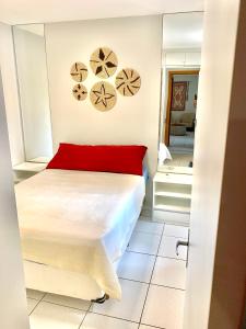 Schlafzimmer mit einem Bett mit einem roten Kissen und einem Spiegel in der Unterkunft Apto Ubatuba home - Centro c vista in Ubatuba
