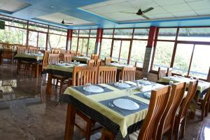 a dining room with tables and chairs and windows at Laurel Heights Resort Idukki in Idukki