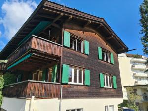 a building with green shutters and a balcony at Grabahus in Arosa