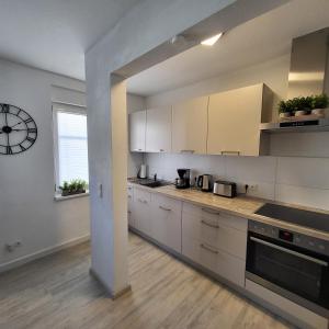 a kitchen with white cabinets and a clock on the wall at Ferienwohnung NR1 in Großräschen