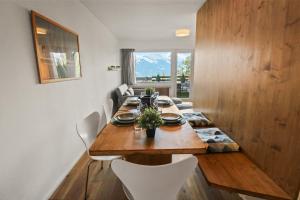 a dining room with a wooden table and white chairs at Superbe appartement avec piscine in Nendaz