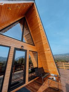 a house with glass doors and a chair on a deck at CABANA 365 in Braşov
