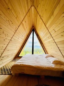 a bed in a wooden room with a large window at CABANA 365 in Braşov