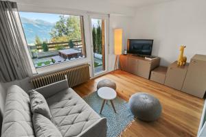 a living room with a couch and a large window at Superbe appartement avec piscine in Nendaz