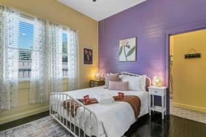 Dormitorio púrpura con cama blanca y ventana en FRIENDS AIRBNB Themed 2bed 2bath walkable to all of Ybor en Tampa