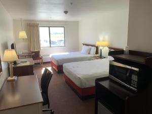 a hotel room with two beds and a television at Oquirrh Mountain Inn in Tooele