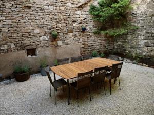 a wooden table and chairs in front of a stone wall at Grande maison - village de Noyers - 5 chambres in Noyers-sur-Serein +10 photos