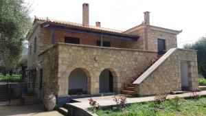 a large stone house with a staircase in front of it at Olive Cottage in Kyparissia