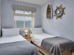 two beds in a small room with a window at Black Rock Hideaway in Porthmadog