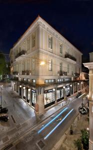 ATHINAIDOS QUARTERS by K&K في أثينا: مبنى ابيض كبير وفيه شارع بالليل