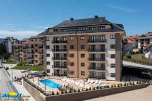 a large apartment building with a swimming pool and chairs at Monix Palace Zlatibor in Zlatibor