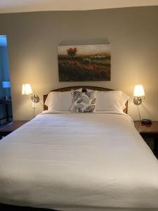 1 dormitorio con 1 cama blanca grande y 2 lámparas en Country Squire Inn and Suites, en New Holland