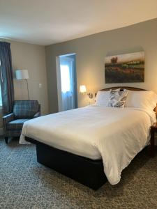 um quarto com uma grande cama branca e uma cadeira em Country Squire Inn and Suites em New Holland