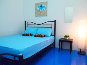 a blue bedroom with a bed with blue sheets at The Cardamom Hostel in Melaka