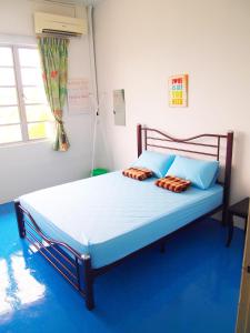 1 dormitorio con 1 cama grande con sábanas y almohadas azules en The Cardamom Hostel, en Melaka