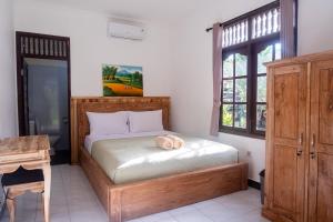 a bedroom with a bed and a table and a window at Sandora Homestay with Private Pool by Supala in Ubud