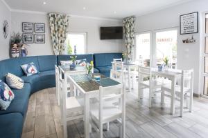 a restaurant with white tables and chairs and a blue couch at Zacisze Sosnowe in Łazy