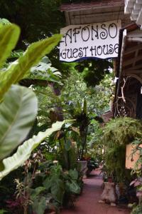 un panneau pour une maison d'hôtes fleurie avec des plantes dans l'établissement Afonso Guest House, à Panaji