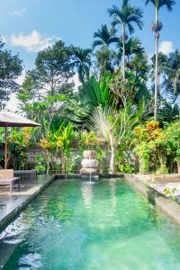 a pool with a fountain in a yard with palm trees at Sandora Homestay with Private Pool by Supala in Ubud