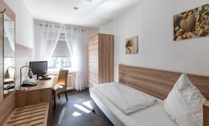ein Schlafzimmer mit einem Bett und einem Schreibtisch mit einem Computer in der Unterkunft Stadt-gut-Hotel Großer Kurfürst in Emden